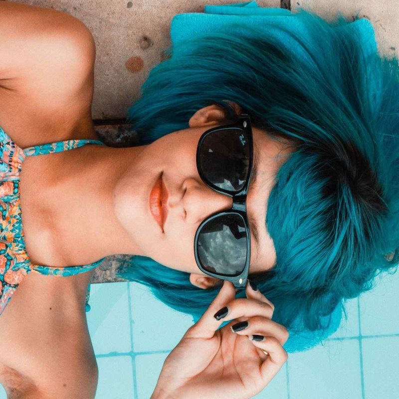 Woman with blue hair and sunglasses.